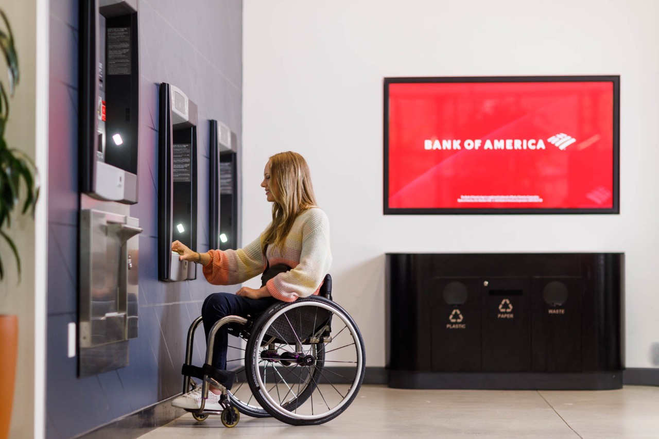 Woman in wheelchair using ATM in Bank of America financial center