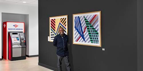 ArtLifting Artist, Rudy Jean-Louis, standing next to his artwork in a New York, NY Bank of America financial center