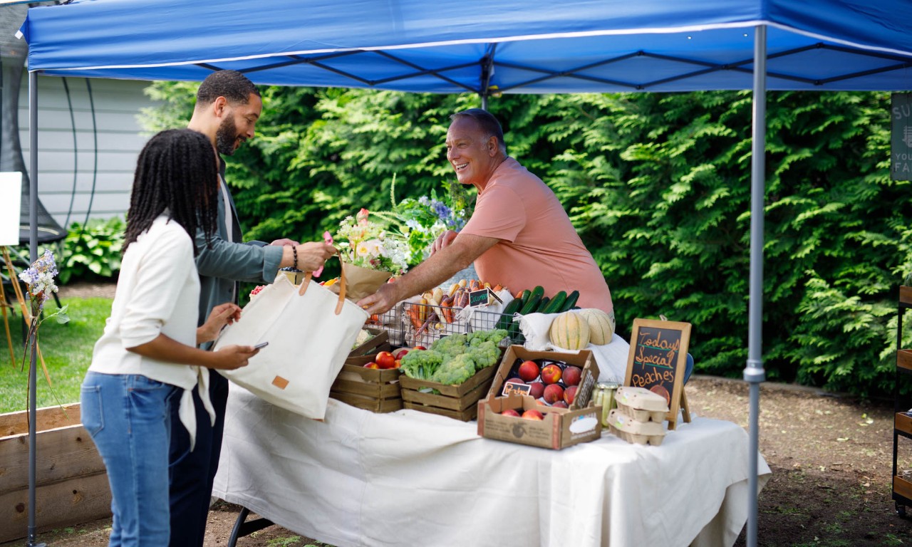Couple makes purchase at farmer's market produce stand